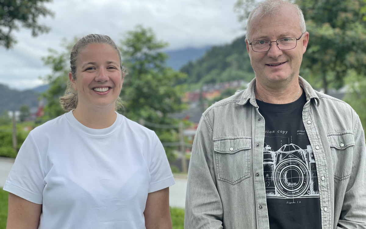 Ung kvinne og middelaldrande mann smiler, ute