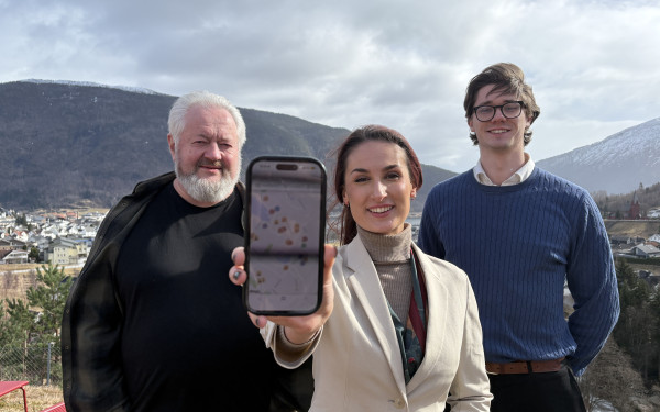 Forskar og gründerar, kvinna i midten held fram mobil med appen Kulturjakten