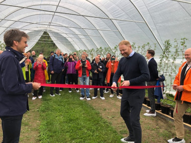 Menn held ei raud snor som blir klypt av ein mann i ein plasttunnel