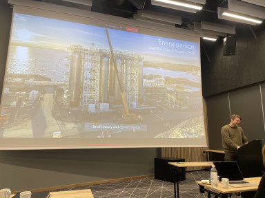 Mann frå kommune fortel om industri, viser stort bilde på lerret